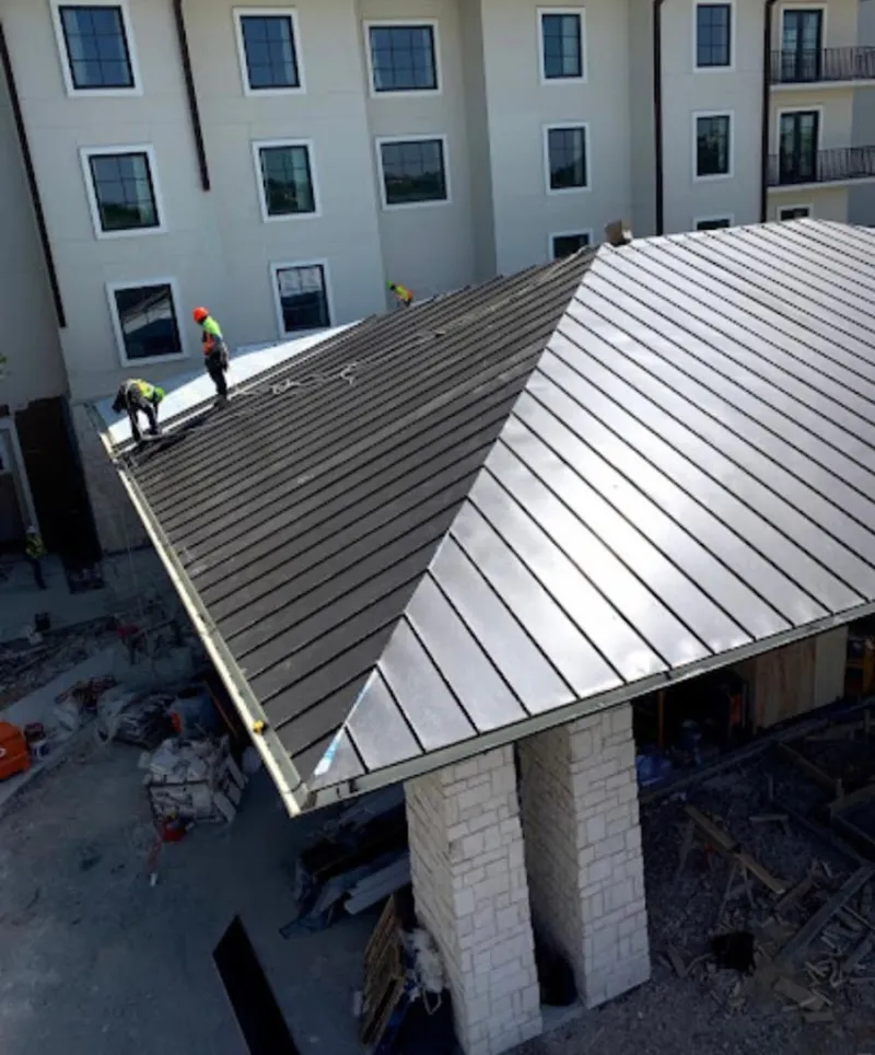 Crew installing standing seam metal roof panels on a commercial project in Patterson